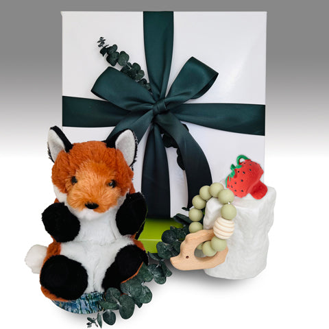 Stuffed fox toy, baby rattle, and gift box with green ribbon on a white background