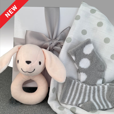 Premium White gift box with a silver bow. Soft pinkish bunny rattle with a smile, 2 pair of fuzzy gray socks with stripes and dots